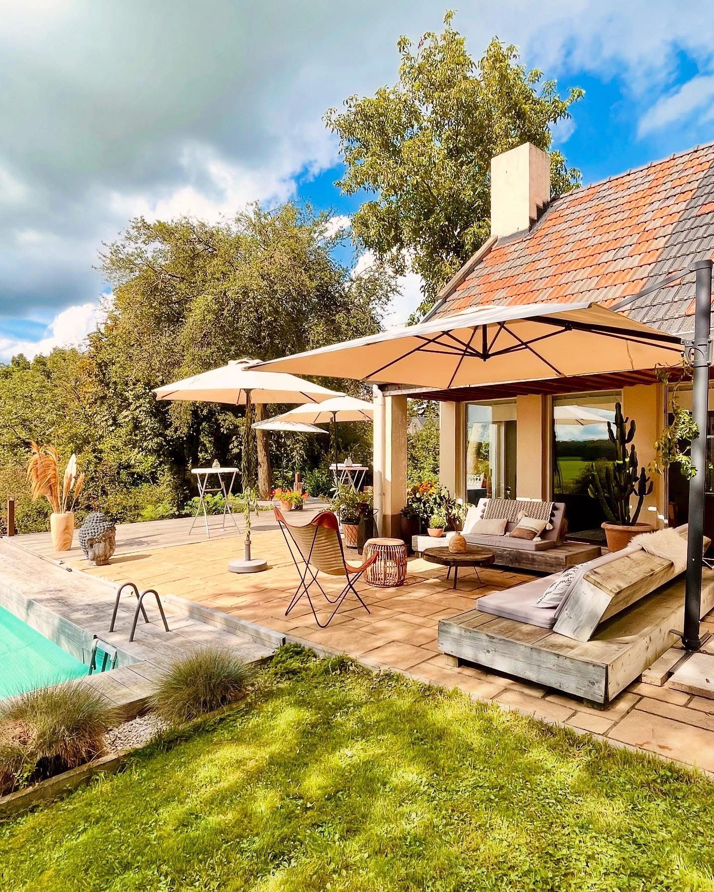 Outdoor patio with a pool, sun loungers, and umbrellas on a sunny day.