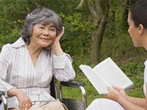 Woman Reading a Book to an Old Lady — Home Health Care in Farmington Hills, MI
