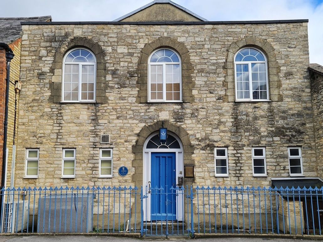 A large brick building with a blue door and arched windows.