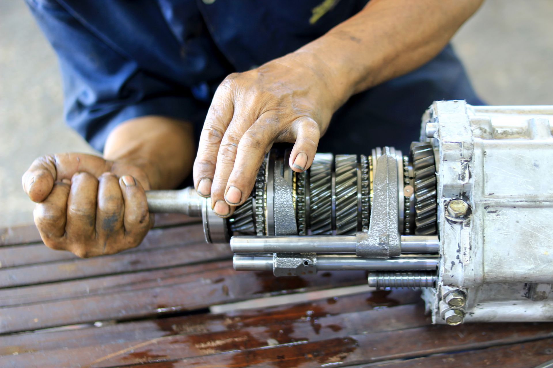 A mechanic repairing a car transmission. A mechanic repairing a car transmission.