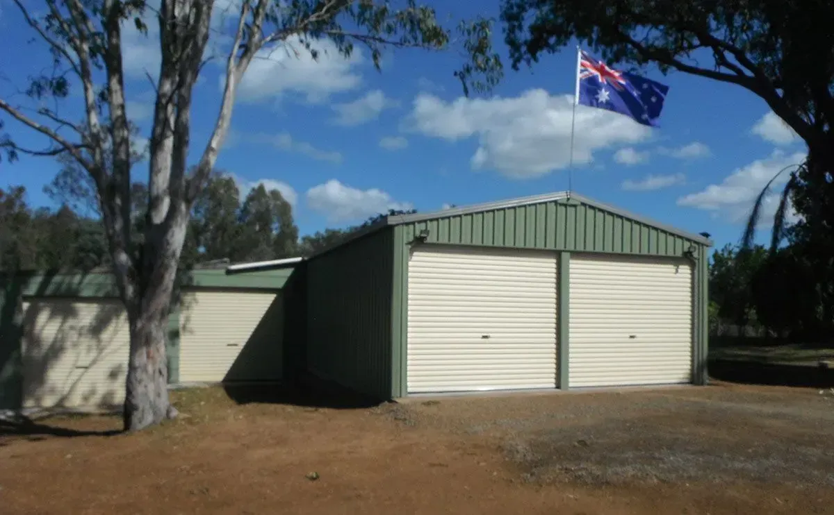 Garage with two doors, green trim, Australian flag. Sunny day with blue sky - Shed Constructions (QLD) In Gin Gin, QLD