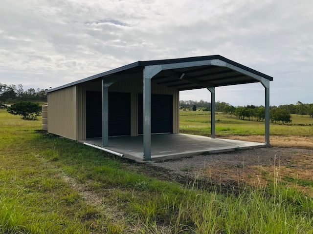 A Garage With A Canopy Is Sitting In The Middle Of A Grassy Field — Shed Constructions (QLD) In Gin Gin, QLD