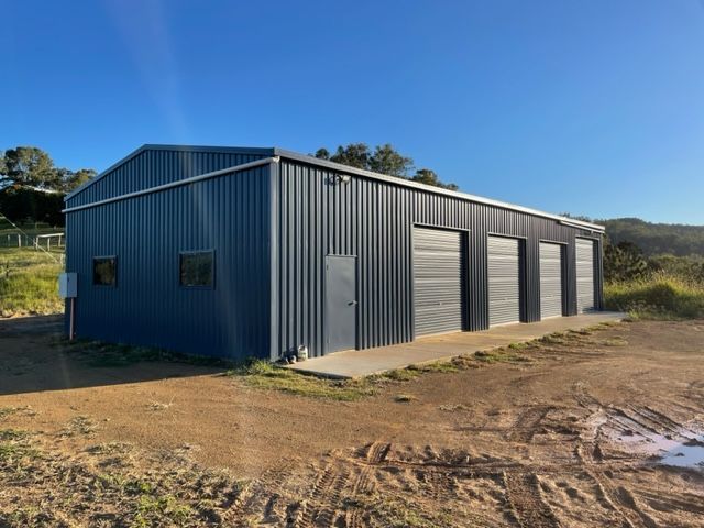 A Large Metal Building Is Sitting In The Middle Of A Dirt Field — Shed Constructions (QLD) In Gin Gin, QLD