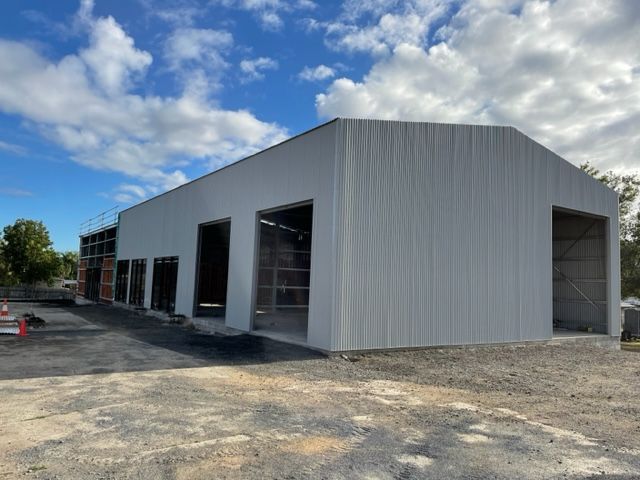 A Large White Building Is Being Built In The Middle Of A Dirt Field — Shed Constructions (QLD) In Gin Gin, QLD
