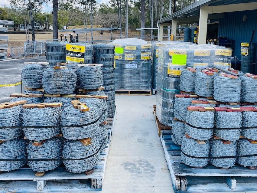 Pallets of barbed wire rolls and fencing materials at an outdoor supply store — Shed Constructions (QLD) In Gin Gin, QLD