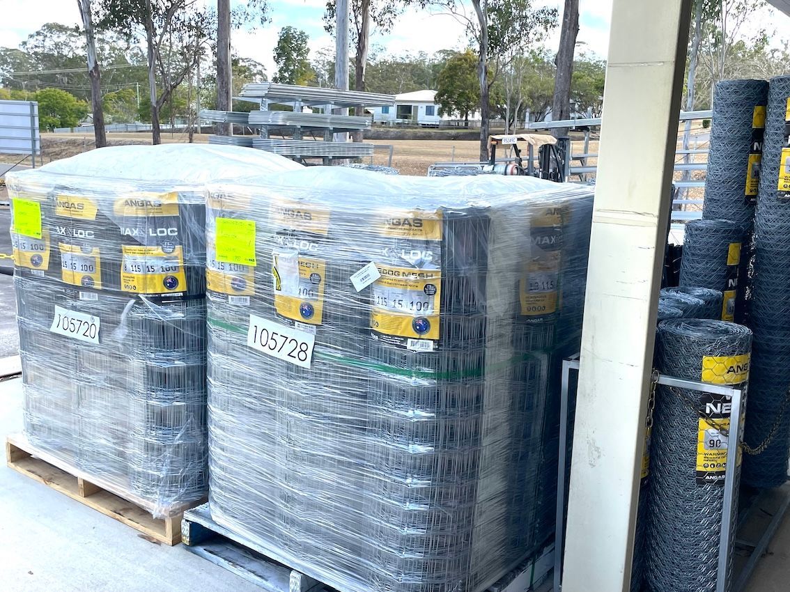 Pallets of rolled wire fencing wrapped in plastic at a store.