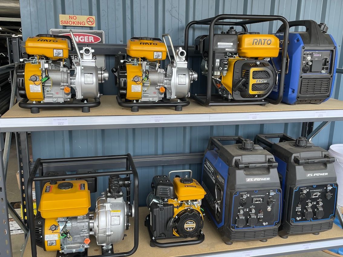 Row of water pumps and generators on shelves, with yellow and black engines - Shed Constructions (QLD) In Gin Gin, QLD