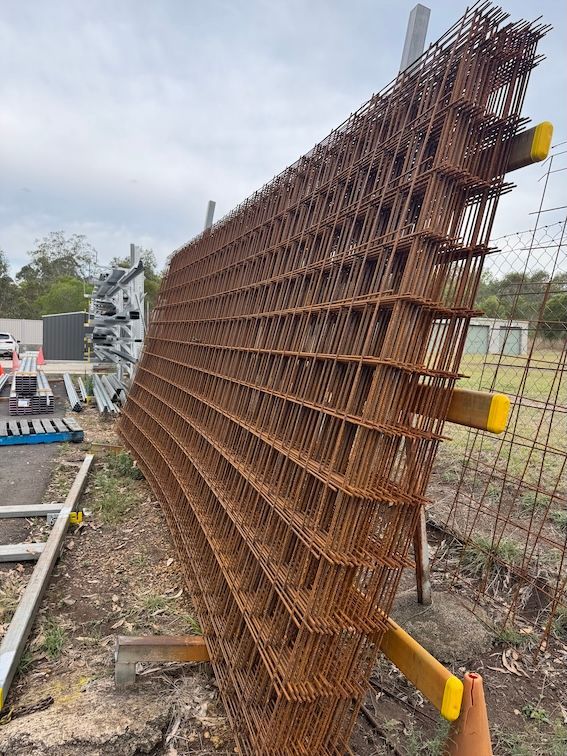 Stacked, rusty metal mesh panels supported by yellow beams, outdoors— Shed Constructions (QLD) In Gin Gin, QLD