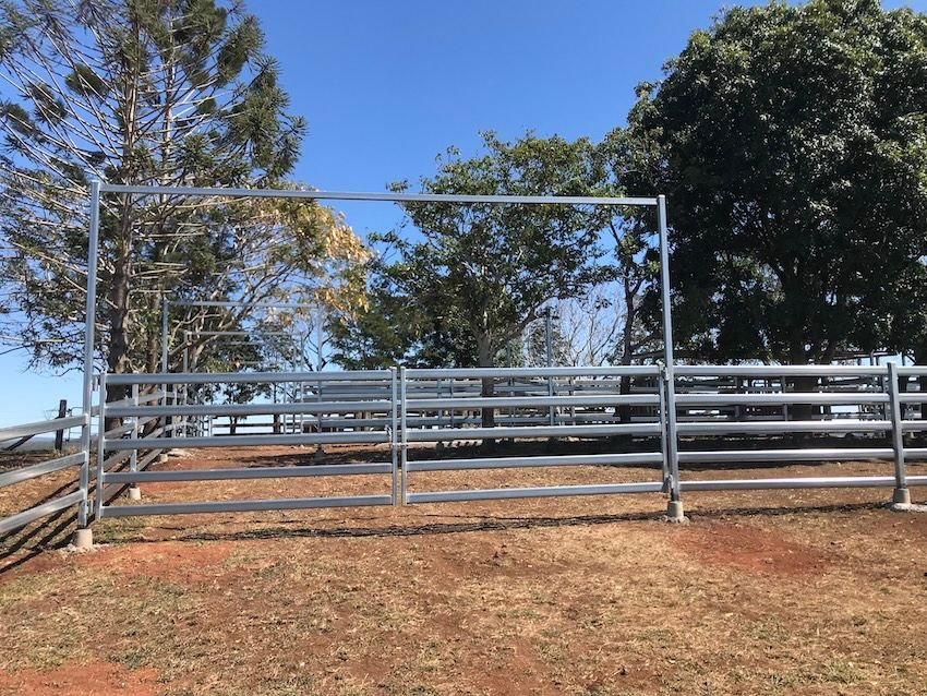 Metal cattle fence on a hillside, under a blue sky, with trees in the background — Shed Constructions (QLD) In Gin Gin, QLD