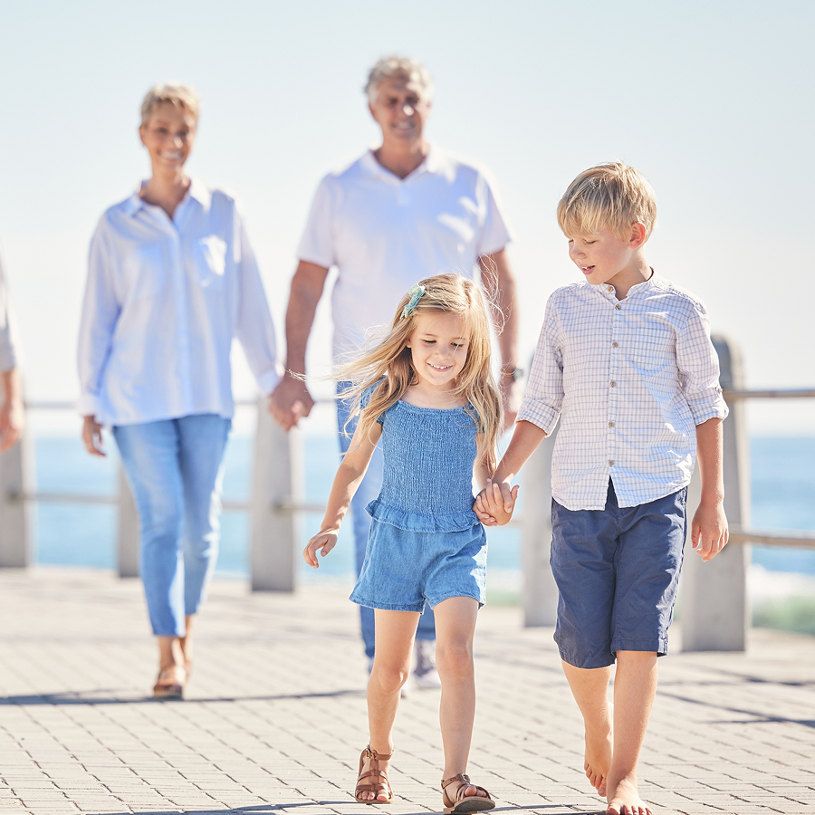 A family is walking on a pier holding hands.