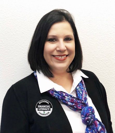 Woman with black bob, smiling, wearing a cardigan, scarf, and a 