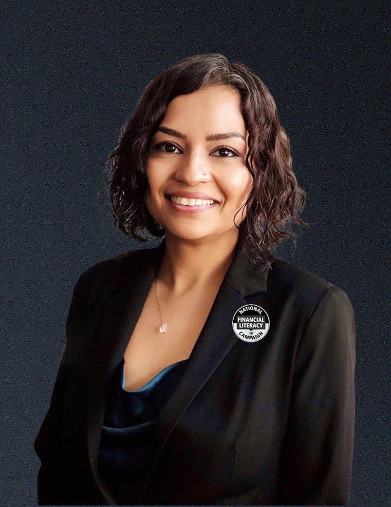Woman in black suit smiles at the camera against a grey backdrop.