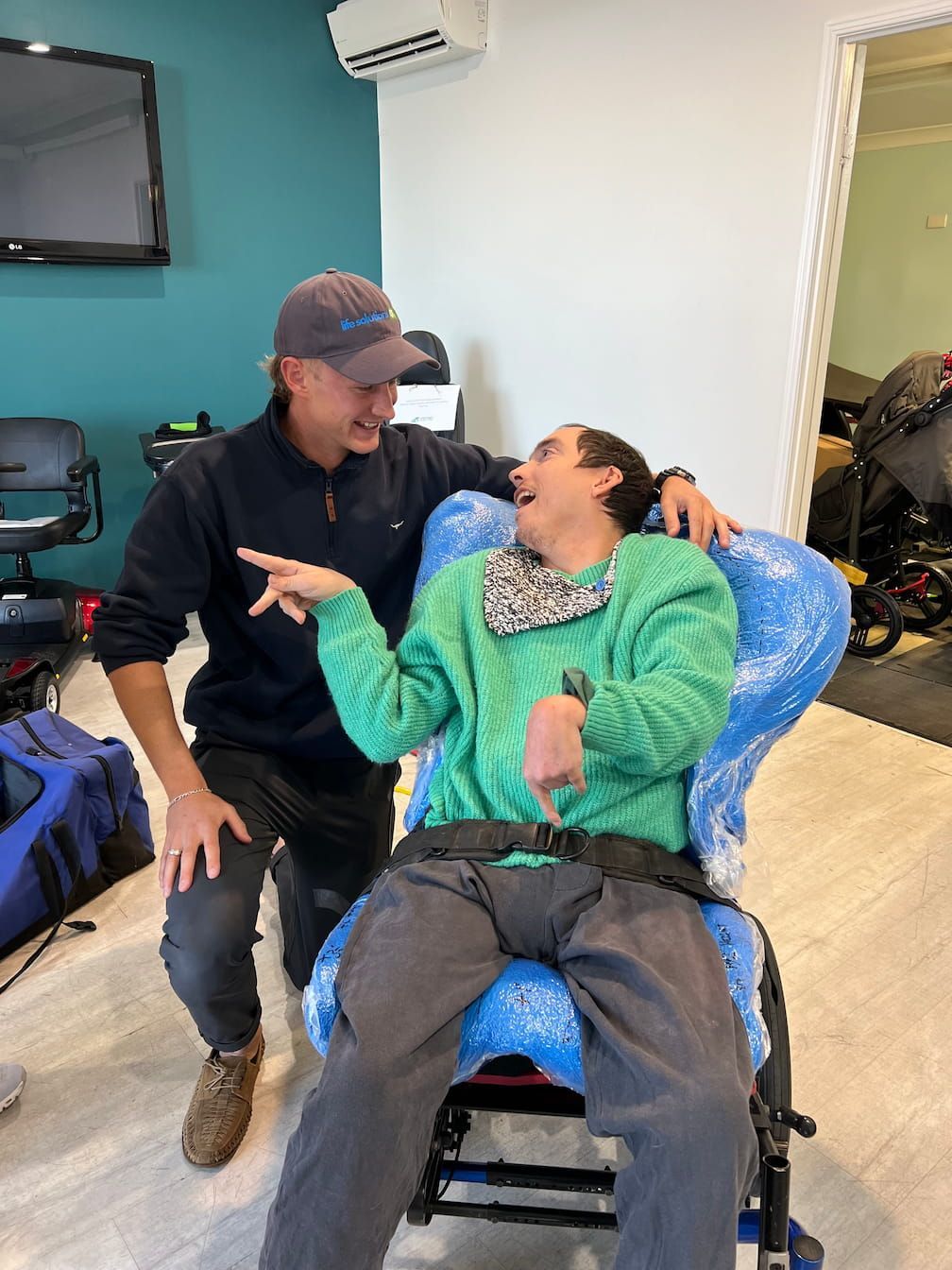 An occupational therapist is sitting next to a man in a wheelchair.