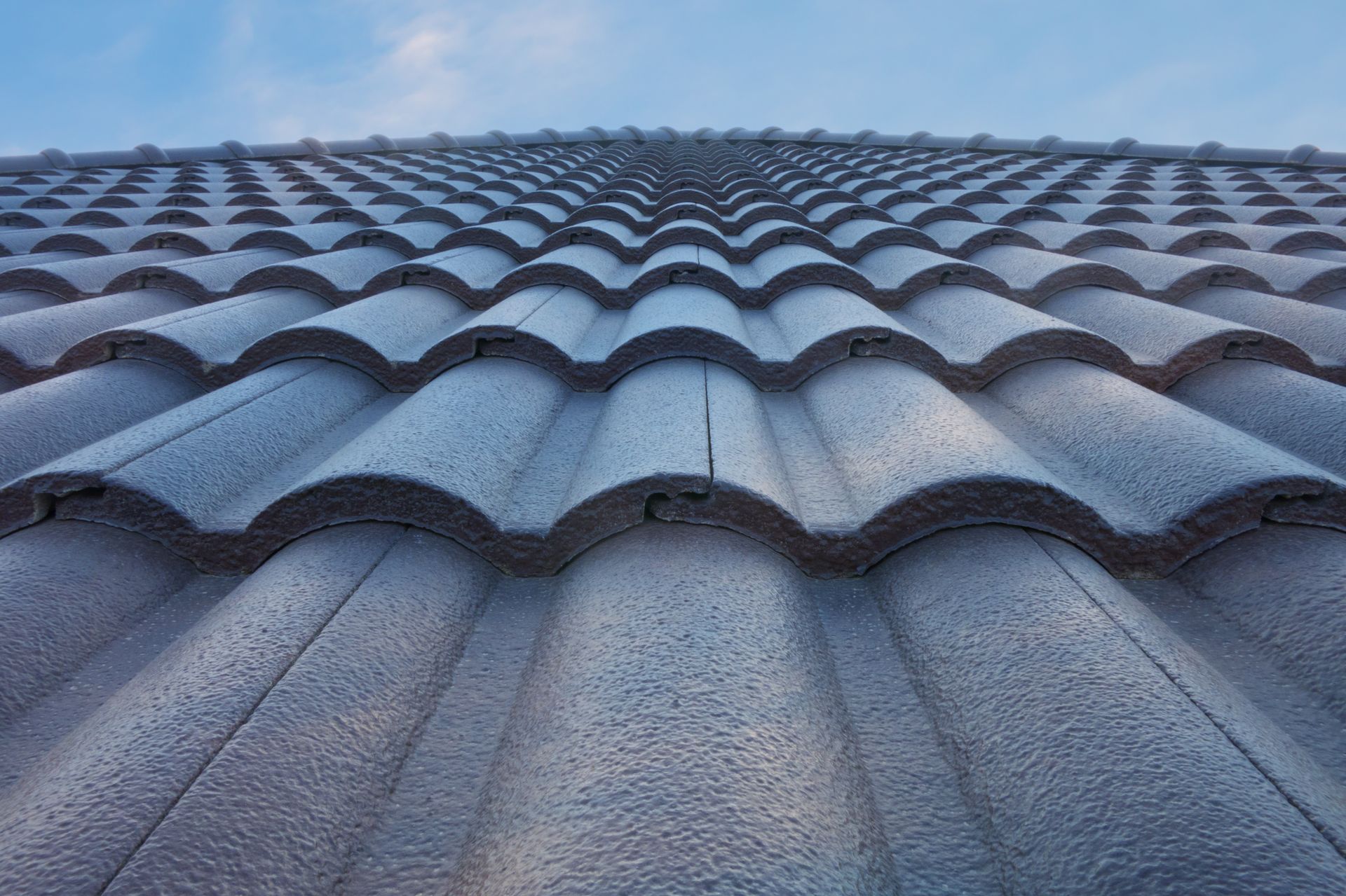 Gray curved roof tiles against a blue sky. Gray curved roof tiles against a blue sky.