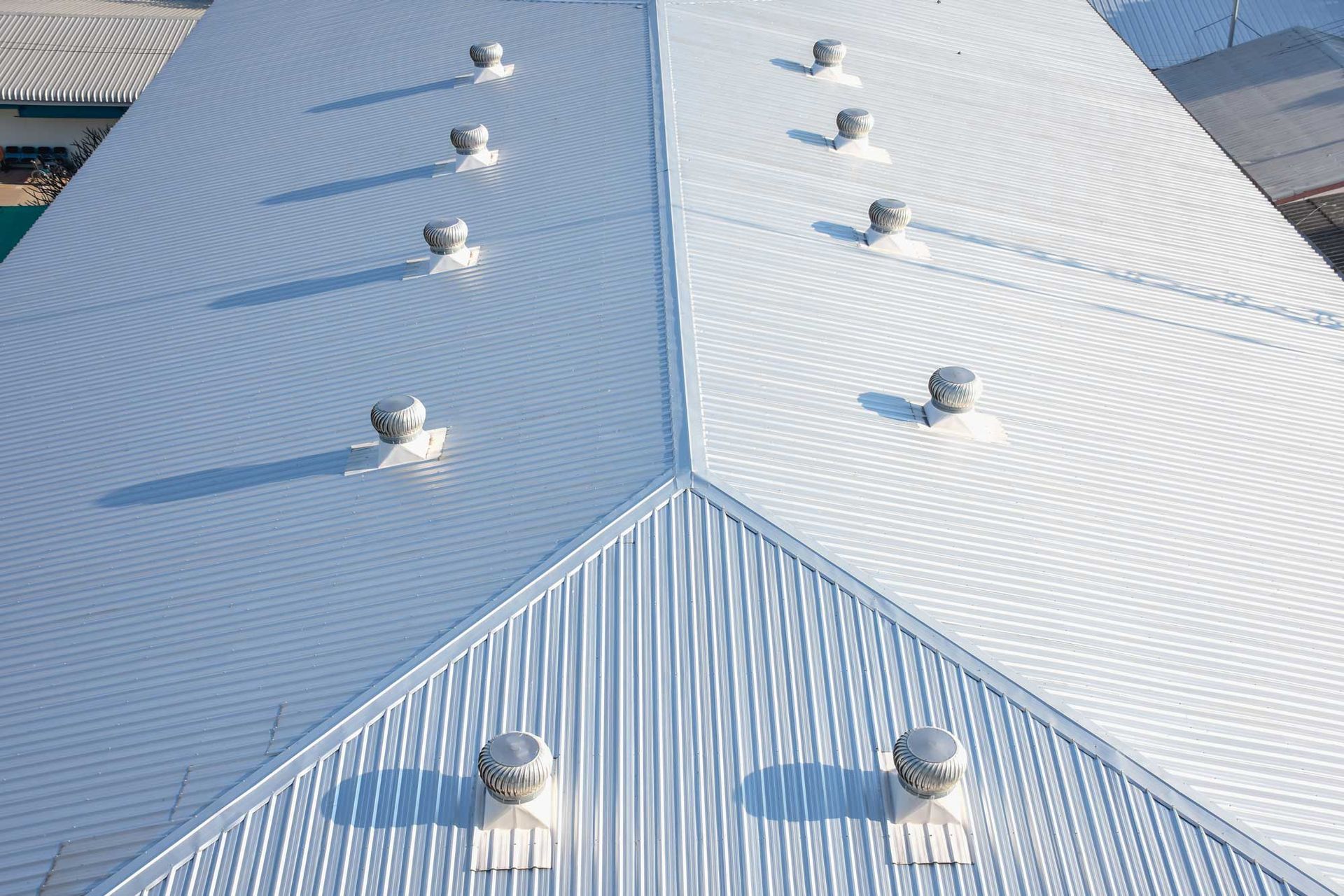 A silver corrugated metal roof with multiple ventilation fans, viewed from above.