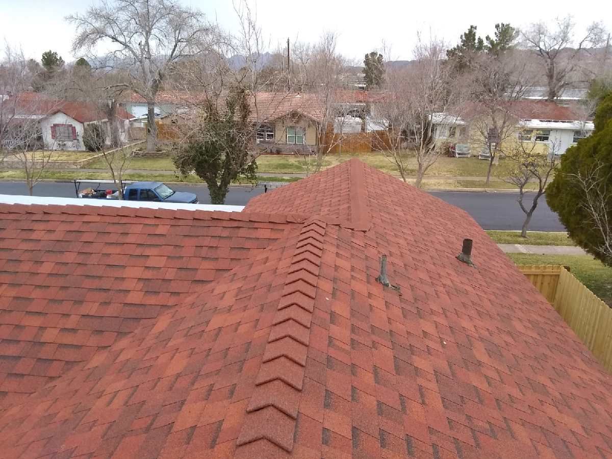Red shingled rooftop with a view of suburban houses and trees in a residential neighborhood.