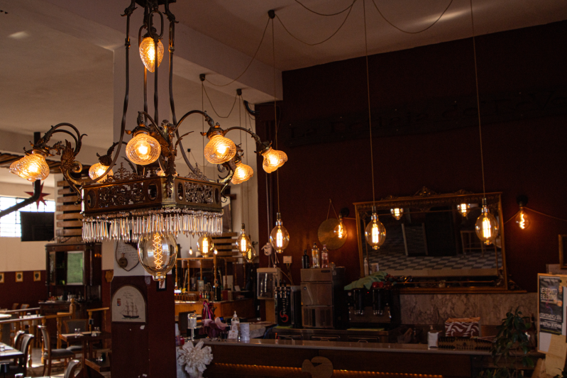 Interno di un ristorante con numerose lampade in stile Edison e un bar. Pareti scure e luci calde.