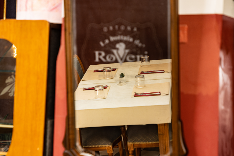 Riflesso speculare di un tavolo da ristorante apparecchiato per quattro persone con bicchieri, tovagliette e uno striscione.