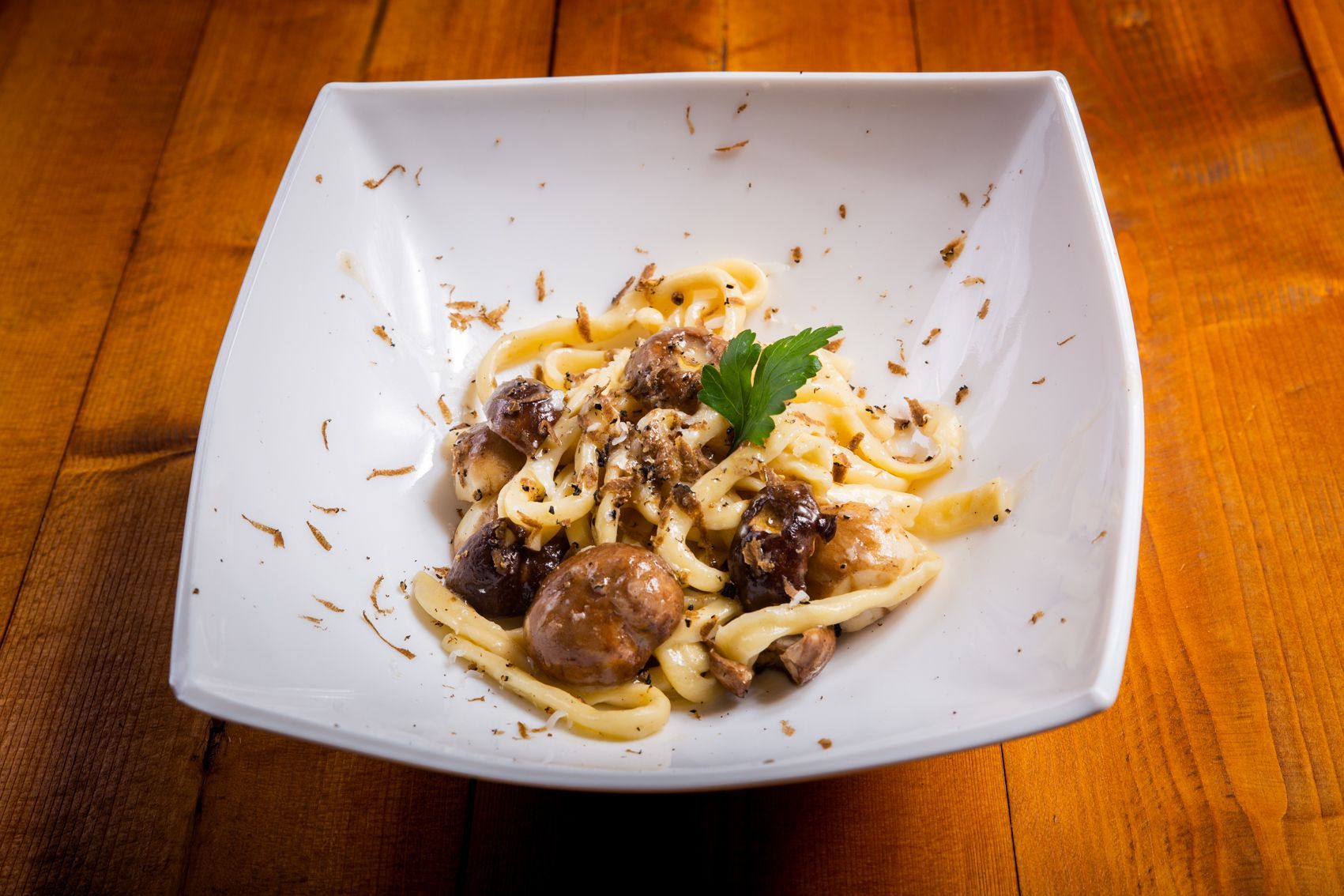 Pizza con besciamella, olive ed erbe aromatiche su un piatto bianco.