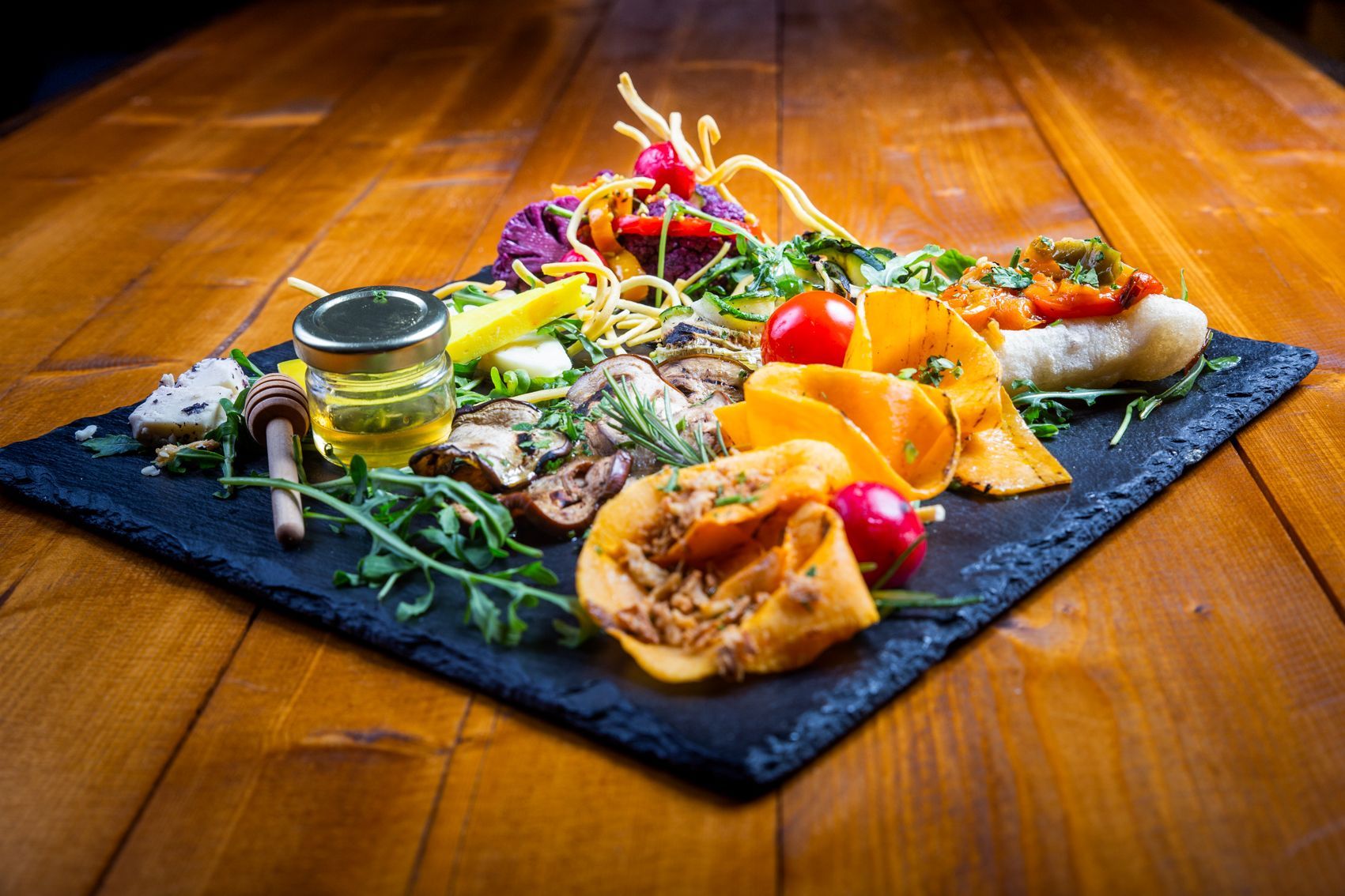 Pollo grigliato su un piatto nero con pomodoro, limone e patate, infilzato con i coltelli.