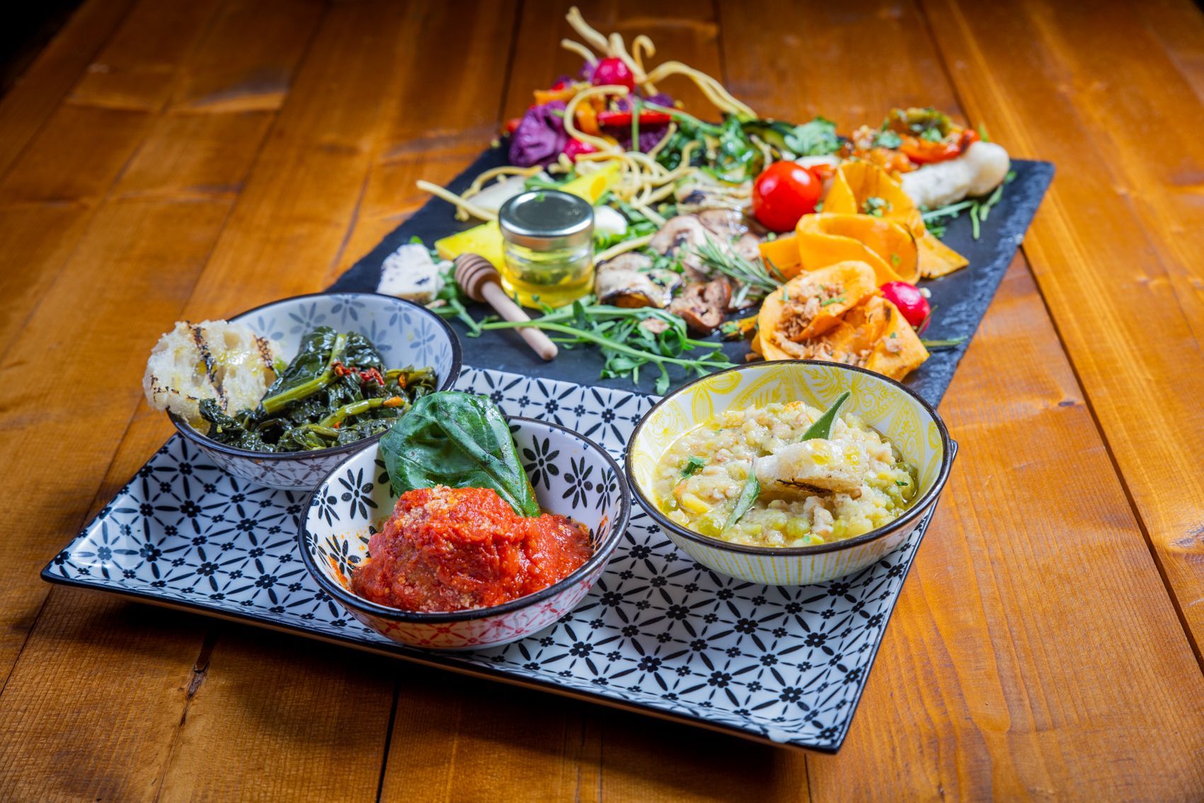 Pizza su un piatto bianco, guarnita con verdure verdi, cipolle e olive nere.
