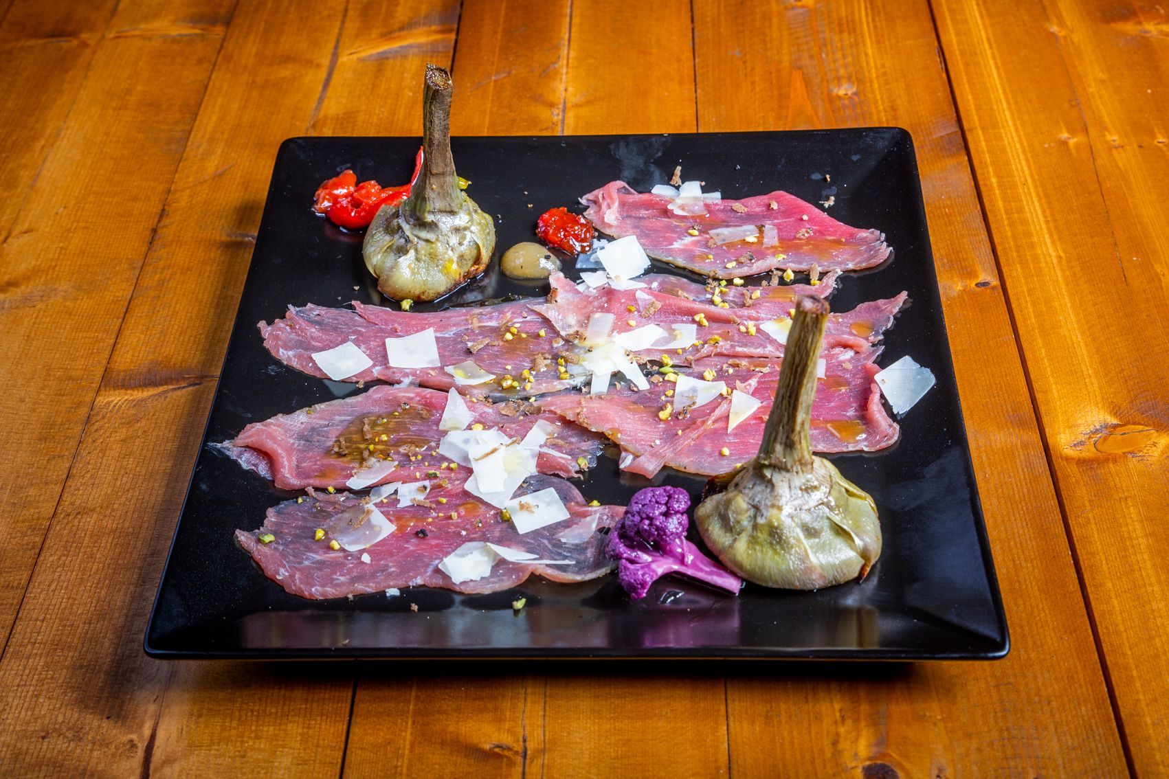 Bistecca alla griglia tagliata con verdure grigliate su un piatto nero.