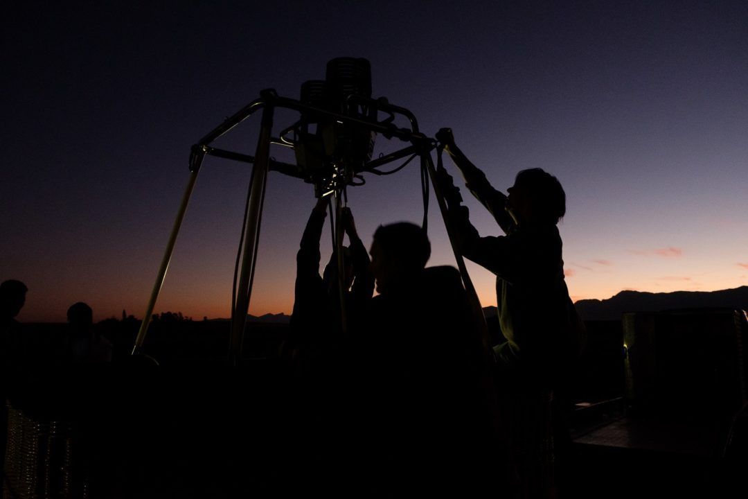 A group of people are silhouetted against a sunset sky