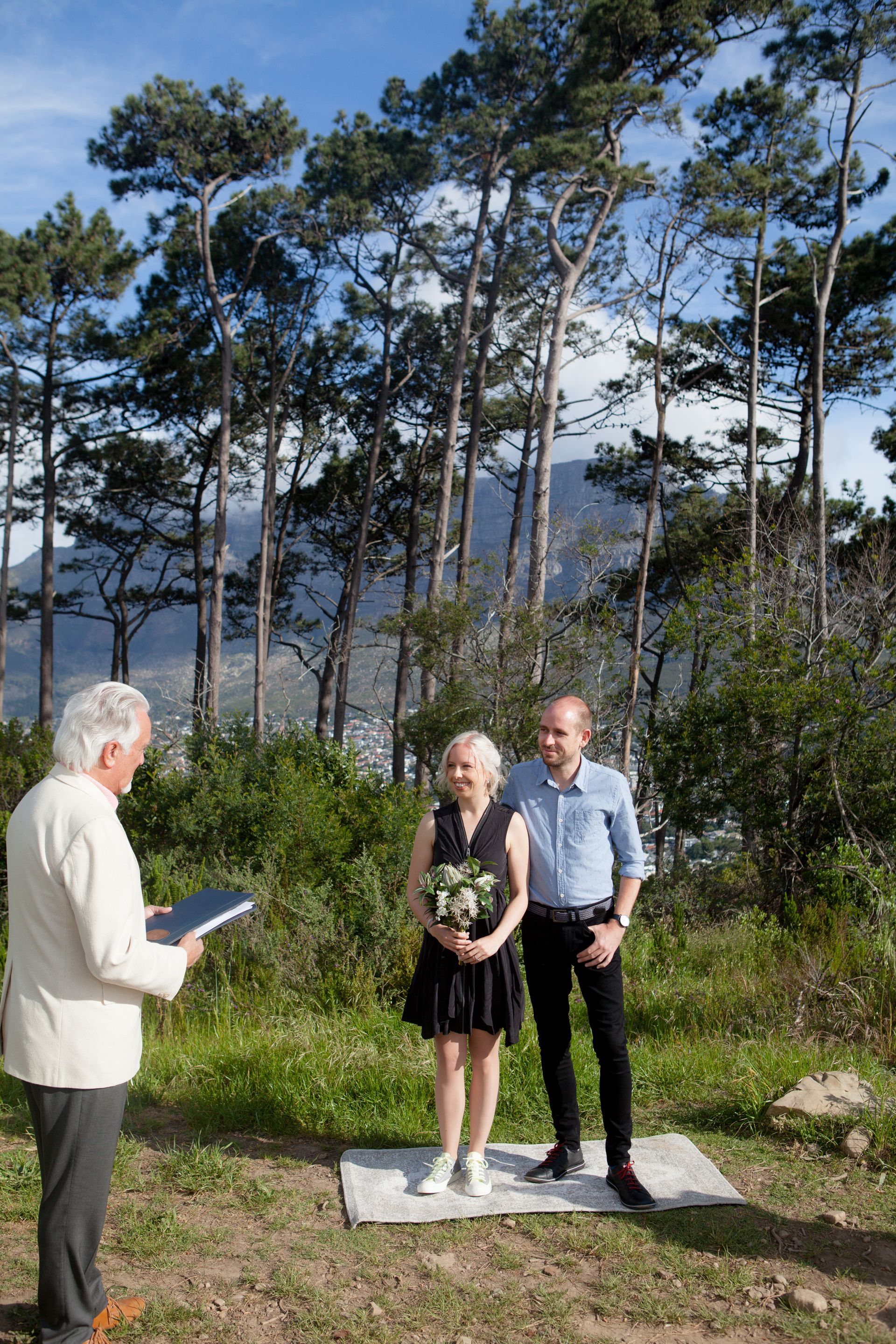A man and woman are standing in a field with trees in the background.
