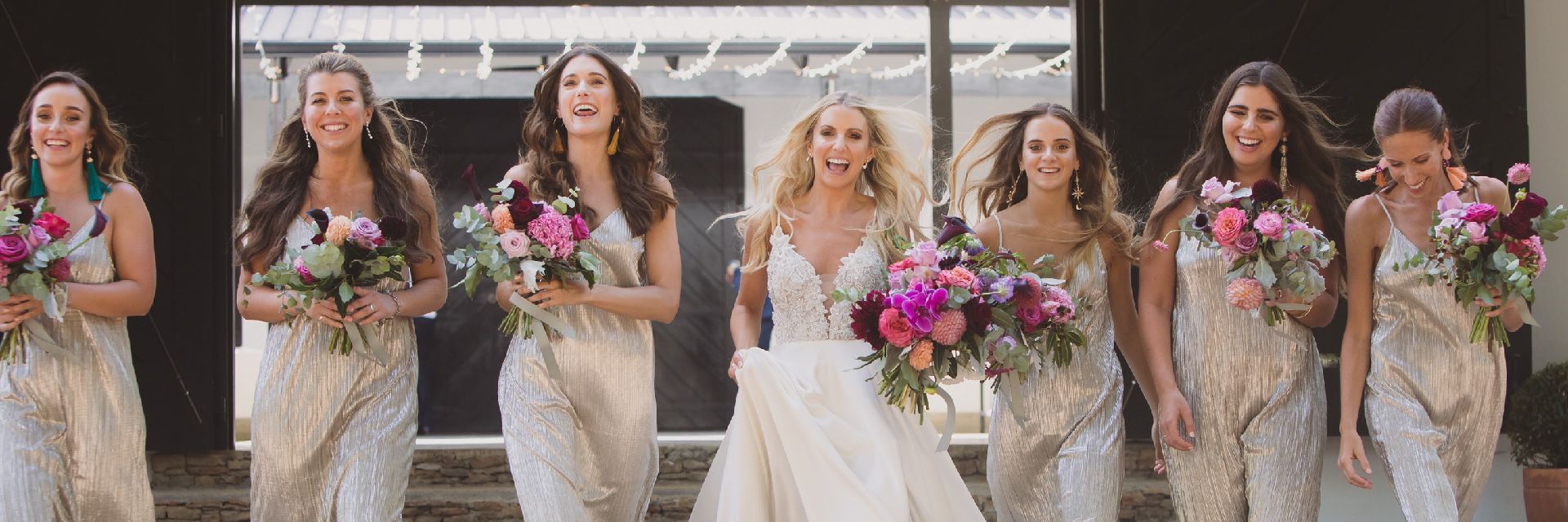 A bride and her bridesmaids are standing next to each other holding bouquets of flowers.