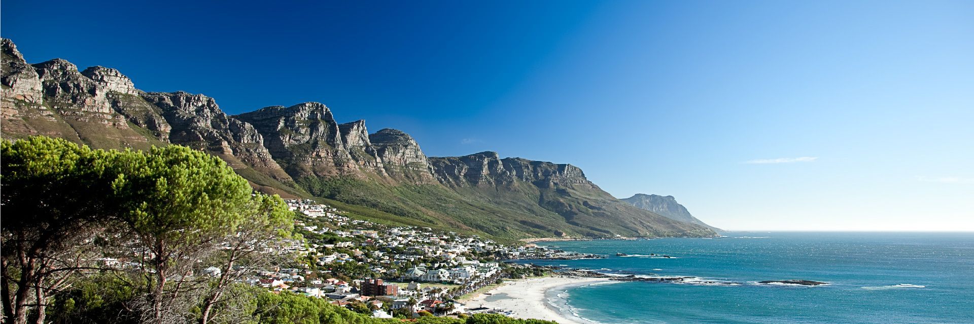 A view of a beach with mountains in the background and the ocean in the foreground.