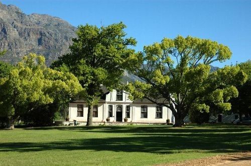 A white house surrounded by trees and grass with mountains in the background