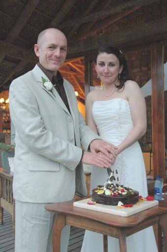 A bride and groom are cutting their wedding cake on a table.