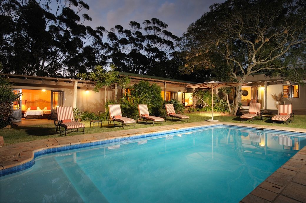 A large swimming pool in front of a house at night