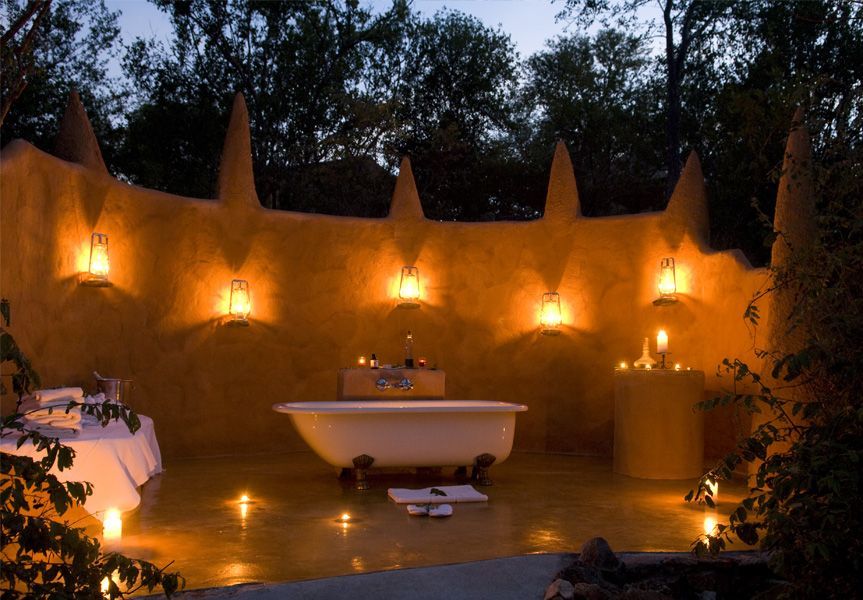 A bathtub surrounded by candles and a wall at night