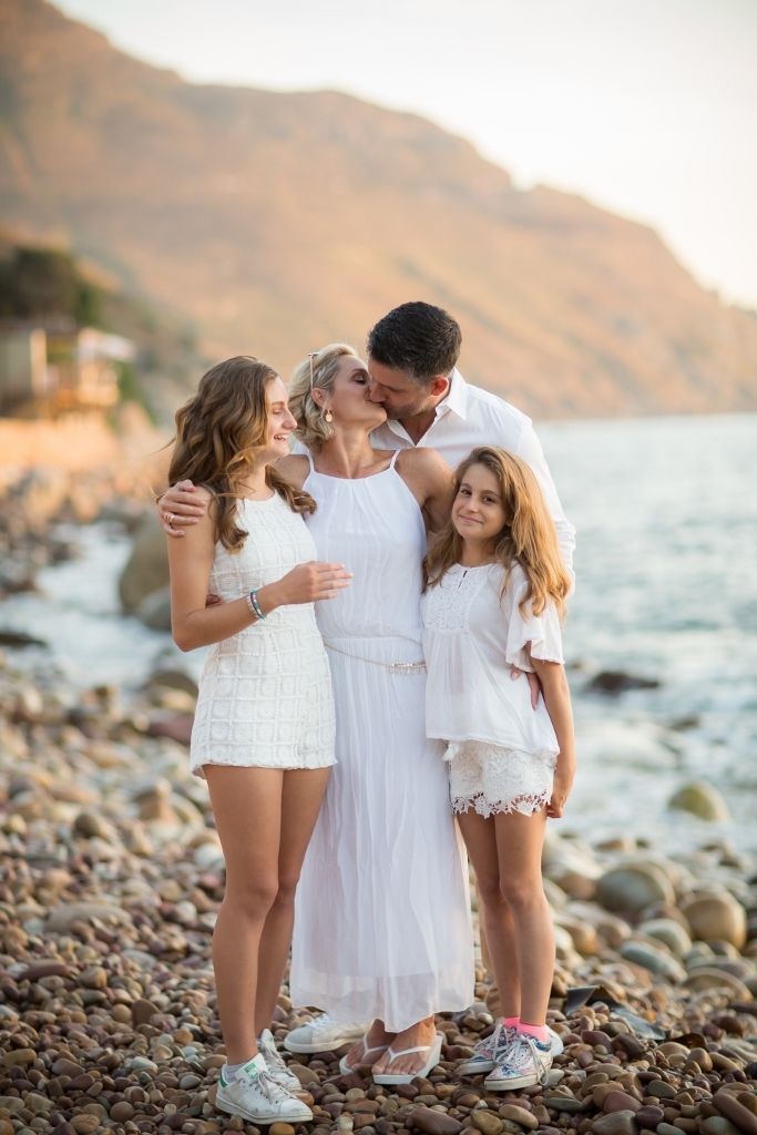 A family is posing for a picture on the beach.