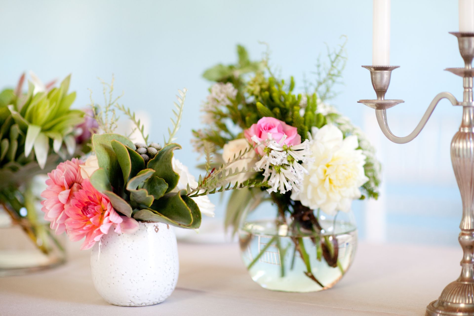 A table with vases filled with flowers and a candle holder.