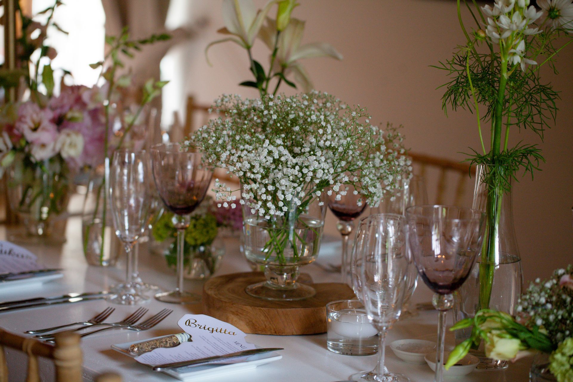 A table set for a wedding reception with flowers and wine glasses.