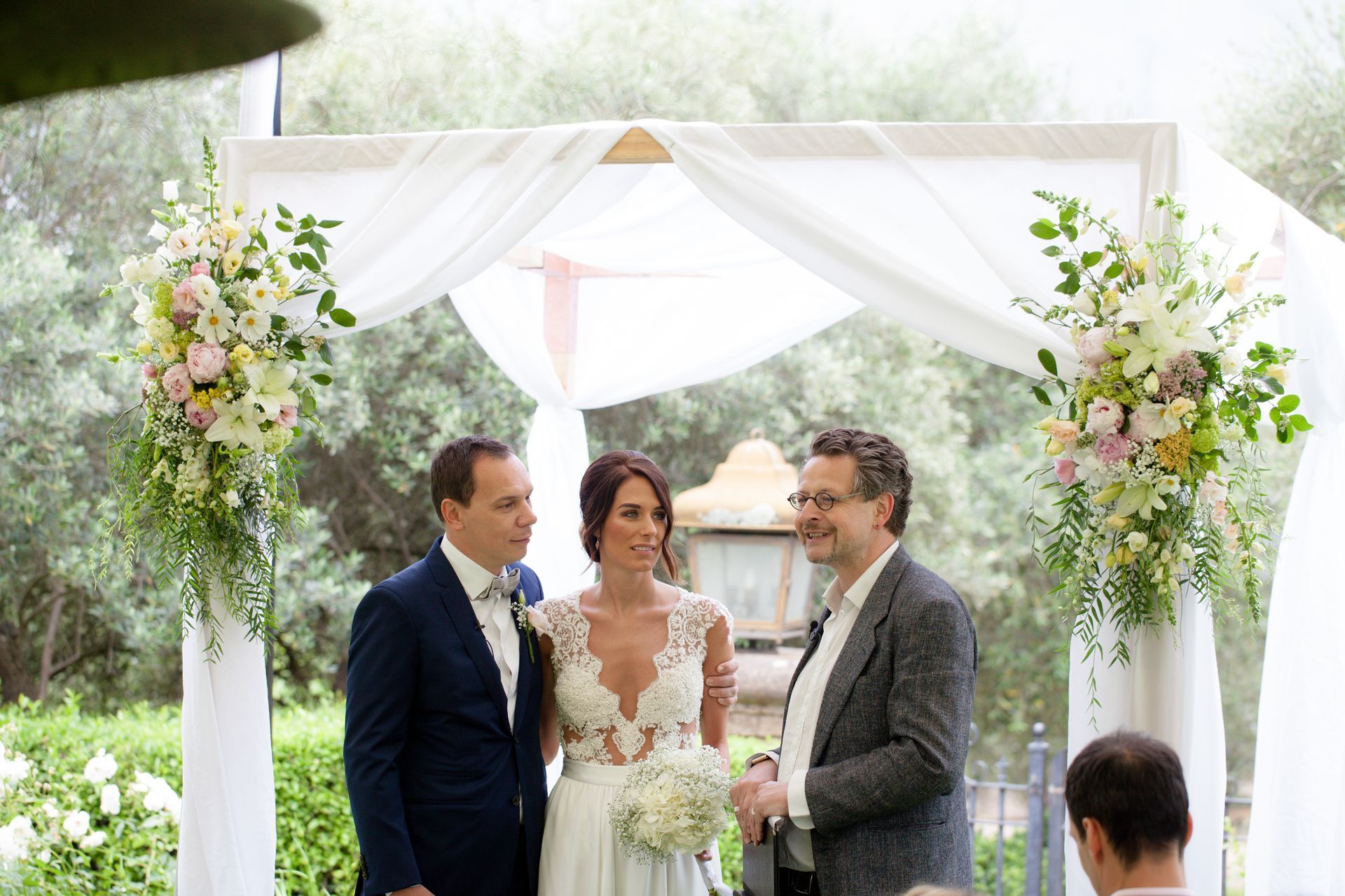 A bride and groom are standing under a white canopy at their wedding ceremony.
