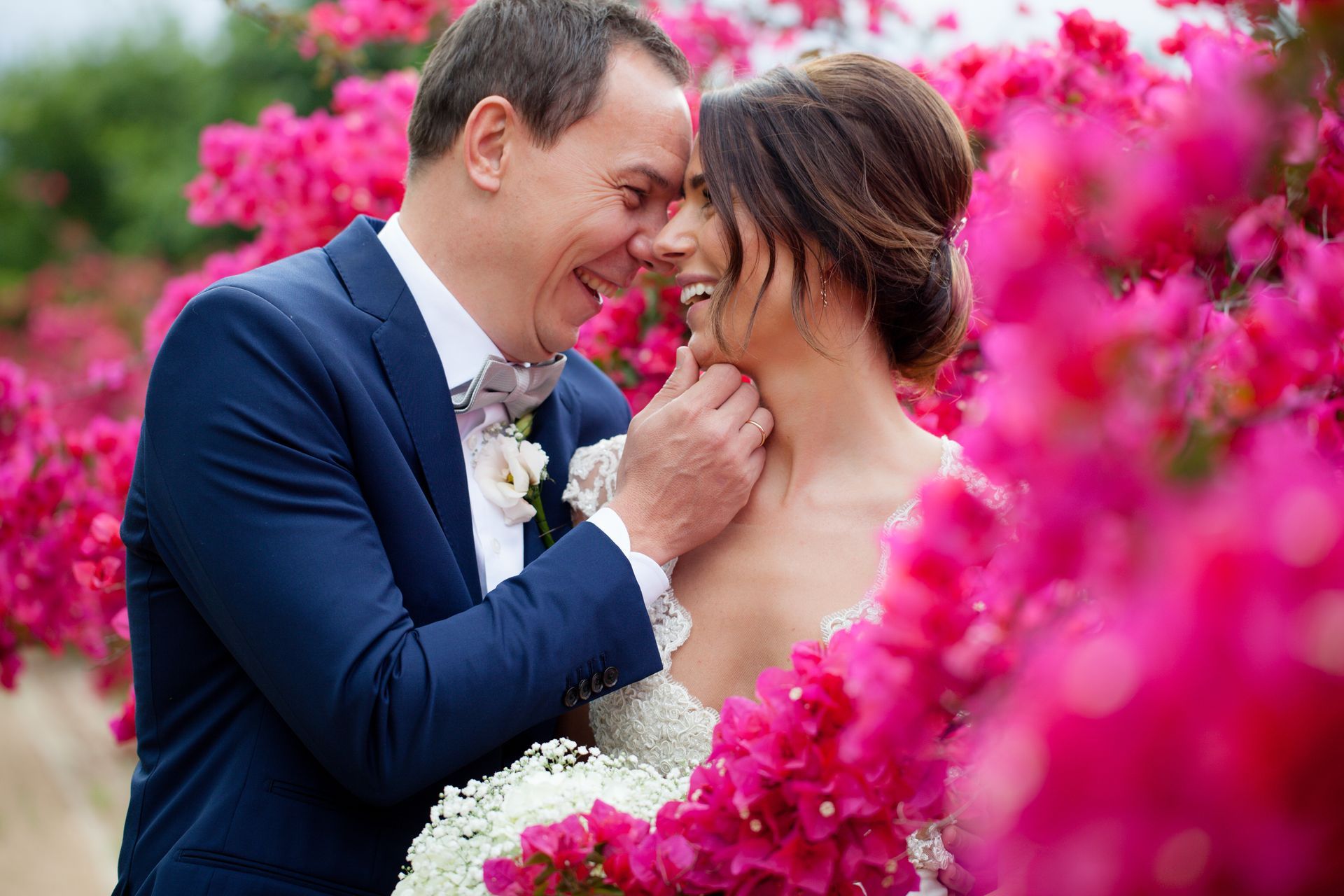 A bride and groom are posing for a picture in a field of pink flowers.