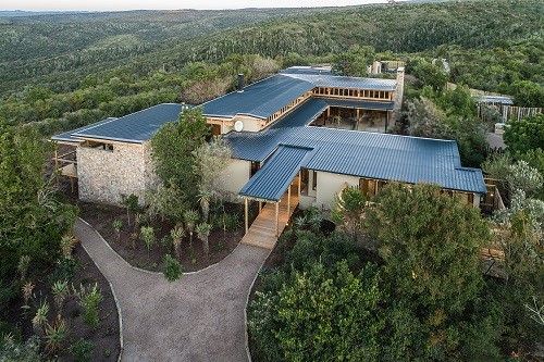 An aerial view of a large house in the middle of a forest.