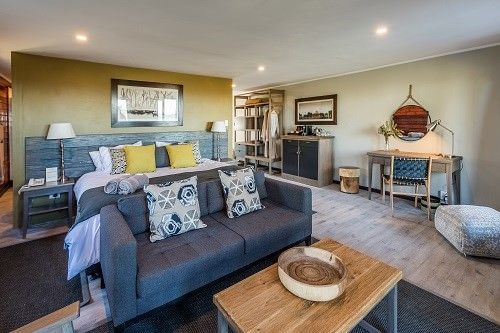 A hotel room with a couch , table and bed.