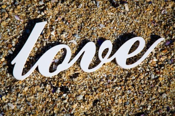 The word love is written in white on the sand