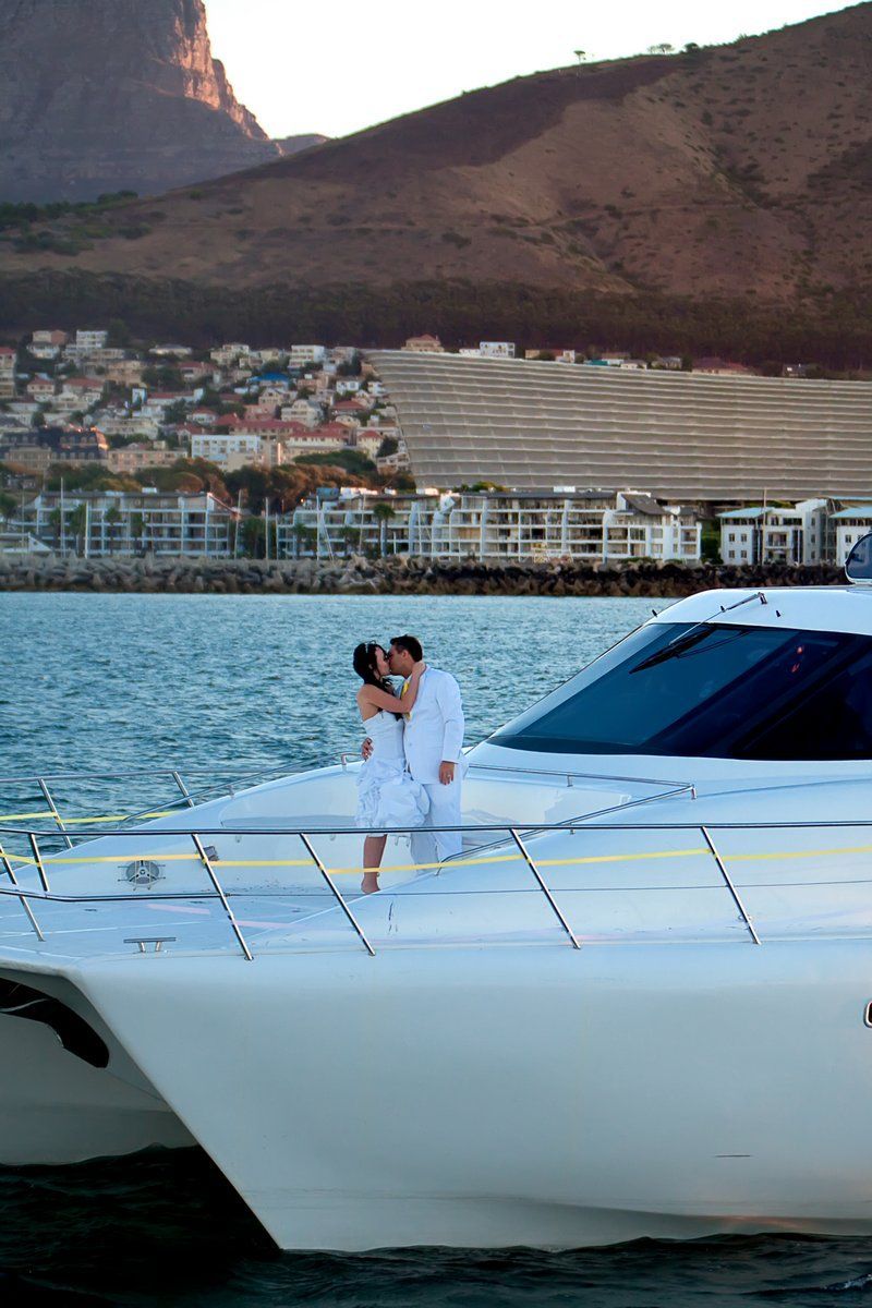 A bride and groom kissing on a boat in the water