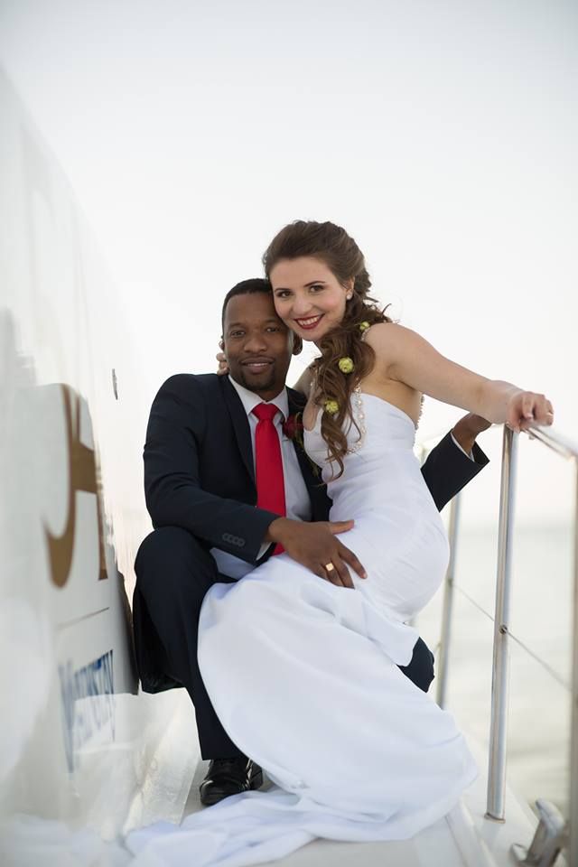 A bride and groom are posing for a picture on a boat.