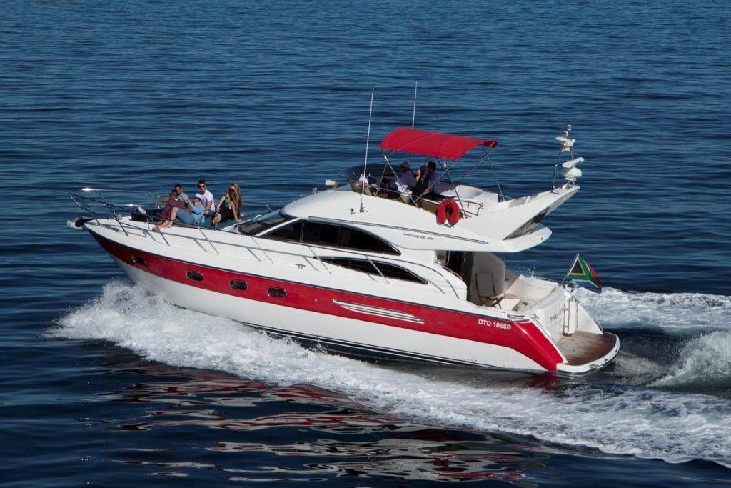 A red and white yacht is floating on top of a body of water.