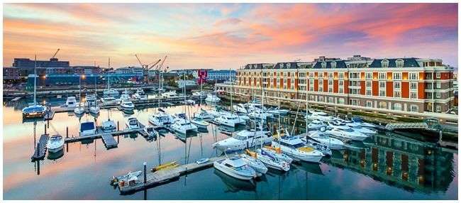 A bunch of boats are docked in a harbor at sunset.