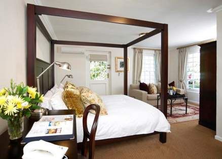 A bedroom with a four poster bed and a desk