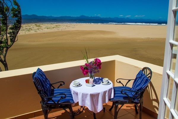 A balcony with a table and chairs overlooking the beach