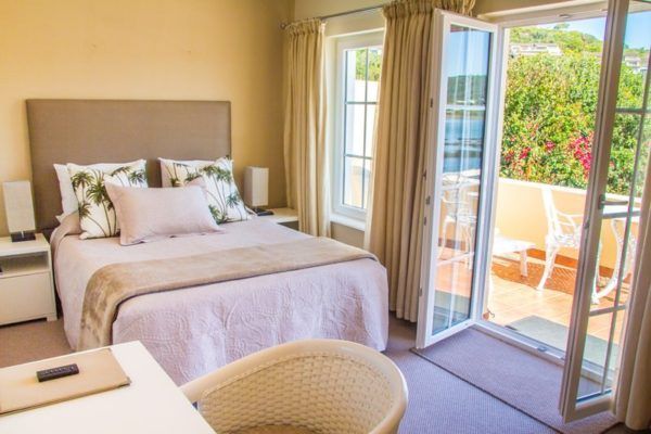 A bedroom with a bed , desk , chair and sliding glass doors leading to a balcony.