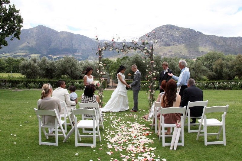 A bride and groom are getting married in a field with mountains in the background